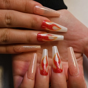 Detail of long coffin press-on nails with nude base, glitter, and red flame art