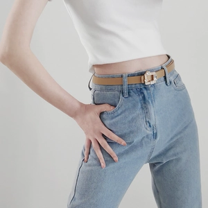 Detail of a thin brown PU leather belt with rhinestone buckle on denim pants