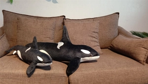 Detailed view of large and small plush orca toys on a dark fabric sofa backdrop