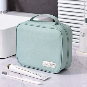 Waterproof mint green travel toiletry bag with zipper on a marble bathroom counter