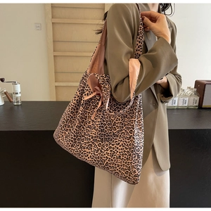 Close-up of leopard print shoulder bag with pink strap worn by a model in a cafe setting