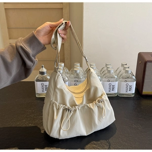 Detail of off-white nylon dumpling bag featuring ruched texture and drawstring side pockets