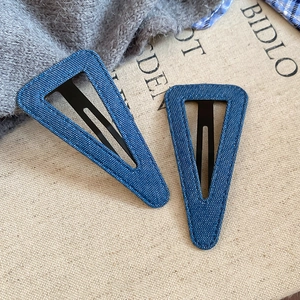 Dettaglio del fermaglio triangolare in tessuto denim a pois blu con clip in metallo nero