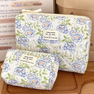 Detail of blue floral quilted makeup bags with woven labels and secure zippers