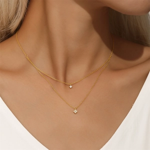 Close-up of a double-layered silver necklace with a sparkling clover and diamond pendant