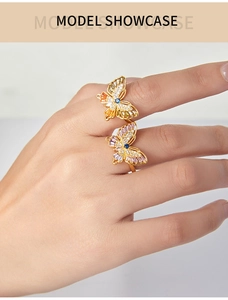Detailed view of two gold butterfly rings with colorful zircons worn by a model