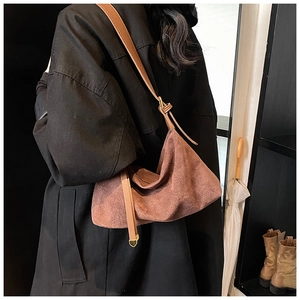 Brown suede slouchy shoulder bag with heart charm detail shown in lifestyle setting