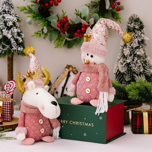 Pink Christmas snowman and reindeer plush figurines on a green holiday gift box