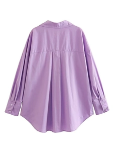 Detail view of the back pleat and hem of a purple poplin long sleeve cotton shirt