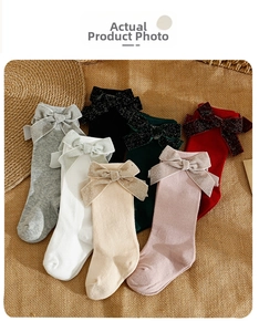 Detailed flat lay of children's knee-high socks with large bows in six assorted colors
