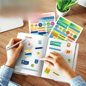 Colorful planning stickers for journals showing monthly themes on a wooden desk setup