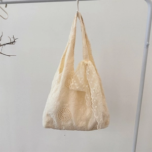 Detailed macro view of off-white lace tote bag with floral embroidery and bow