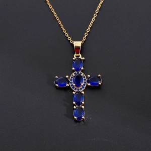 Close-up of golden cross pendant with blue zircons on a delicate chain necklace