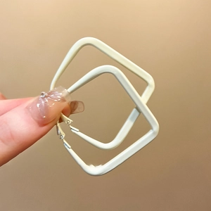 Detailed view of modern white square hoop earrings with a minimalist polished metal finish