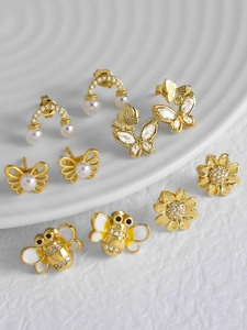 Détail de boucles d'oreilles plaquées or 18k avec perles, abeilles, papillons et cristaux
