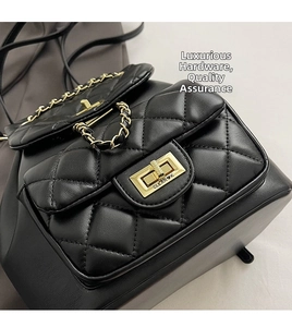 Close-up of quilted black leather backpack featuring golden metal logo turn-lock and chain