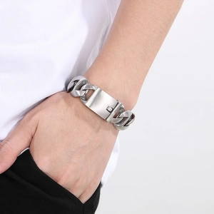 Detail of a matte silver Cuban chain bracelet with a brushed metal rectangular clasp