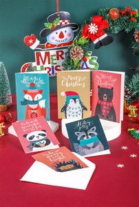 Close-up of 6 Christmas cards with animal illustrations and white envelopes on red table