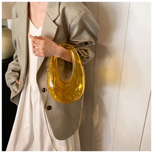 Close-up of yellow acrylic U-shaped evening bag with a golden metal chain strap