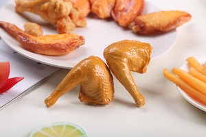 Detailed close-up of realistic PVC chicken wing food model with glossy texture on white plate
