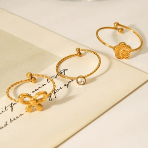 Detailed view of 18K gold plated bow and daisy ring set on an artistic paper background