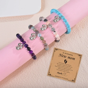 Detailed close-up of 8mm beaded bracelets with silver footprint charms on display