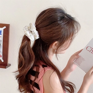 Close-up of floral print scrunchie on a ponytail with premium satin texture