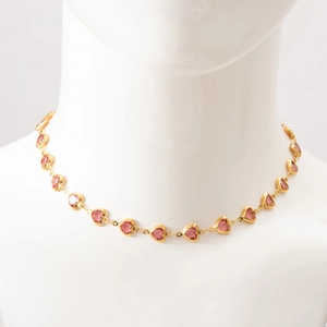 Detailed view of a gold-plated heart necklace with pink gemstones on a white bust