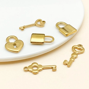 Close-up of 6 gold plated stainless steel heart lock and key charms on ceramic plate