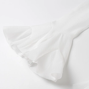Detail of white crepe fabric flare sleeve with delicate textured ruffle design
