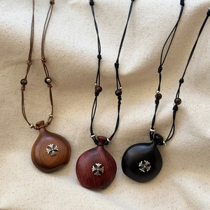 Detail of wooden calabash pendants with silver gothic cross on textured fabric