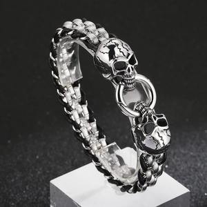 Macro shot of silver stainless steel skull bracelet with black braided leather band