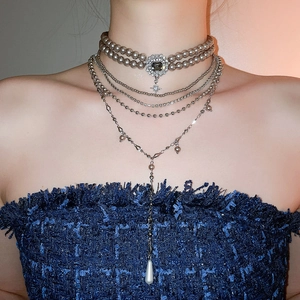 Detail of layered pearl necklace featuring teardrop pendant and grey square stone choker