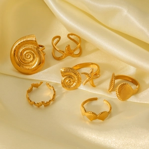 Detailed close-up of gold shell and starfish rings on elegant silk background fabric