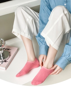 Close-up of pink low cut ankle socks with heel tab on model in a cozy setting