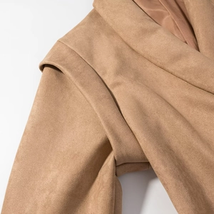 Macro shot of faux suede texture and tailored lapel on camel long sleeve jacket