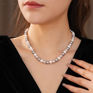 Detail of multi-color pearls necklace with white and grey beads on black velvet garment