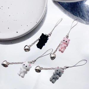 Flat lay of colorful flocked cat charms with heart bells on a white reflective surface