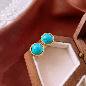 Detail view of retro turquoise stud earrings with gold metal base on wooden jewelry box