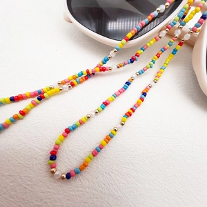 Detailed close-up of rainbow glass seed beads with gold accents on a glasses strap