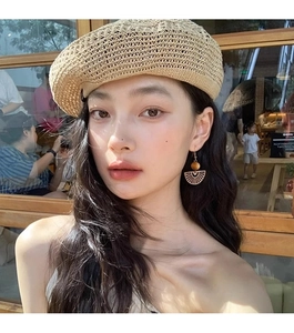 Close-up of ethnic fan-shaped hollow pendant earrings with wooden beads on model