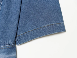 Detail der Jeanskleid-Manschette mit blauem Waschstoff und gelben Doppelsteppnähten