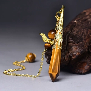 Macro detail of hexagonal tiger eye crystal pendant with golden wings and fine chain