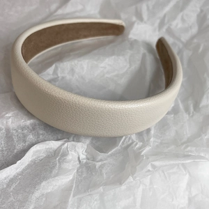 Detail showing the white lychee leather texture and brown velvet lining of the headband