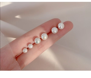 Detail of 925 silver needle pearl earrings featuring high luster round white pearls