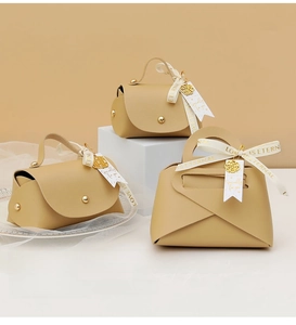 Close-up of beige leather wedding favor box with gold hardware and ivory floral ribbon