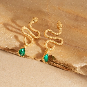 Detail of gold snake earrings featuring scale textures and green teardrop stone pendants