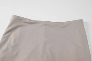 Detail view of smooth beige woven fabric and neat stitching on high waist trousers