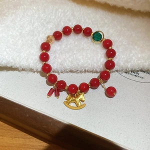 Dettaglio macro del braccialetto di perle di agata rossa con ciondolo a cavallo dorato