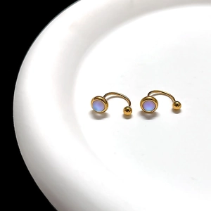 Macro view of gold moonstone tassel earrings with rainbow luster on white ceramic